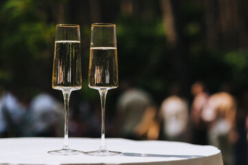 Two glass glasses of champagne are on the table with a white tablecloth.