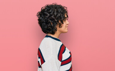 Young hispanic woman with curly hair wearing casual clothes looking to side, relax profile pose with natural face with confident smile.