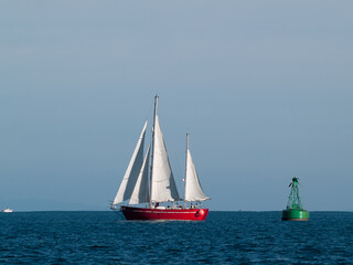 Classic style yacht with red hull sails past