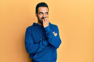 Young hispanic man wearing casual clothes looking stressed and nervous with hands on mouth biting nails. anxiety problem.