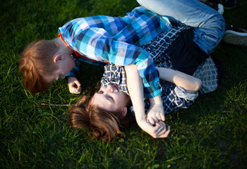 Boy and girl teenagers are fighting on the grass in nature