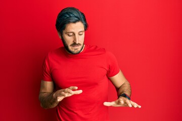 Fototapeta premium Young hispanic man wearing casual red t shirt disgusted expression, displeased and fearful doing disgust face because aversion reaction.