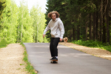 A young man rides a skateboard in the park in the summer.