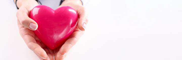 Female hand holding red toy heart closeup