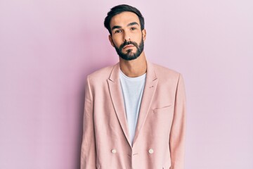 Young hispanic man wearing business jacket relaxed with serious expression on face. simple and natural looking at the camera.