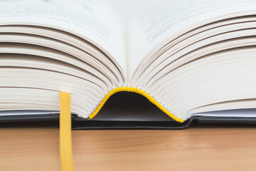 Open book with a bookmark on a wooden table close-up.