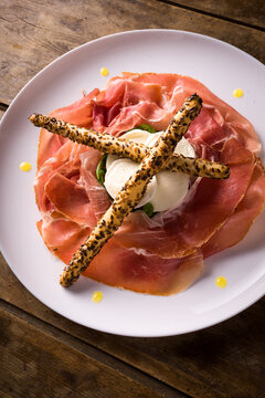 plate with San Daniele raw ham and buffalo mozzarella from Campania on wooden table. detail