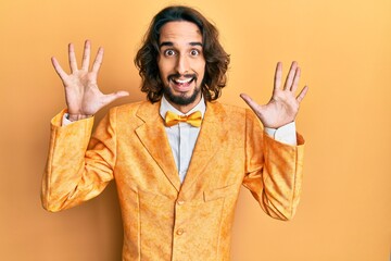 Young hispanic man wearing hipster elegant look showing and pointing up with fingers number ten...