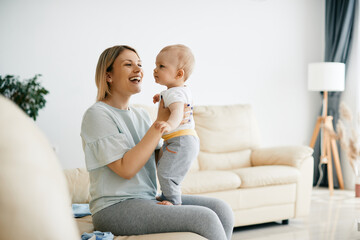 Young happy mother enjoying in time she is spending with her small son at home. Cheerful mother having fun with her baby boy.