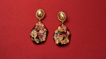 Close up shot of luxury gold earrings with precious stones isolated over red background