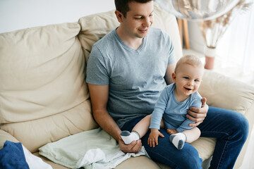 Young happy father spending time with his baby son at home.