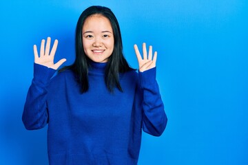 Young chinese girl wearing casual clothes showing and pointing up with fingers number nine while...