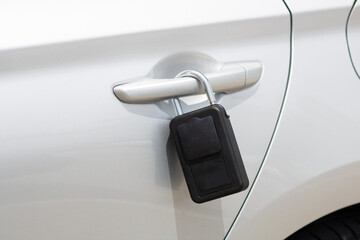 Close-up of portable padlock key safe security box attached to a car door handle containing car or...