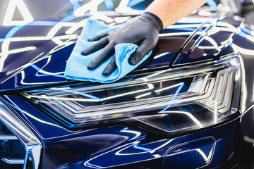 A man cleaning car with microfiber cloth, car detailing (or valeting) concept. Selective focus..