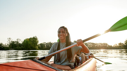 Active young woman smiling, enjoying a day kayaking together with her boyfriend in a lake on a late...