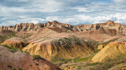 Yellow mounds and colorful red rocks and dramatic mountains in the Badlands National Park - South...