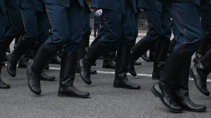 Close-up of the feet of military personnel marching in a parade in slow motion. Military march. Blue uniform. clothes and black boots