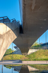 View on a concrete bridge above water in a business district of a city; trees and plants in the background