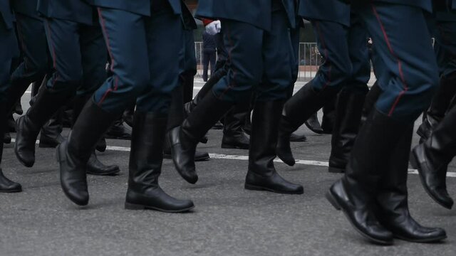 Close-up of the feet of military personnel marching in a parade in slow motion. Military march. Blue uniform. clothes and black boots