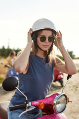 Fototapeta premium Happy young caucasian girl sitting on retro scooter