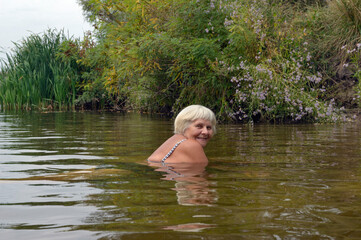 Woman is posing in the river water in cloudy day.
