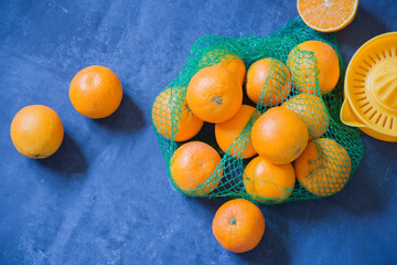 oranges scattered on a blue background for squeezing juice with a manual squeezer