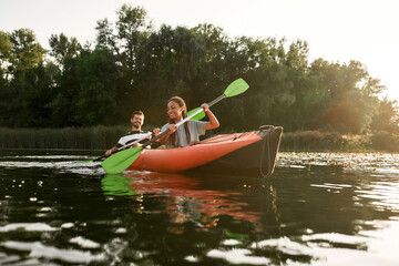 Young couple of friends having fun, kayaking in a river surrounded by the beautiful nature on a summer day