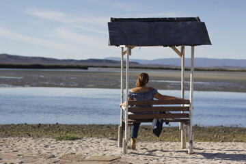 mujer sentada en banco mirando el agua