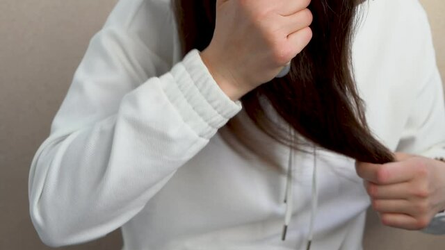A girl combs her long, thick red hair in close-up against a white background.	