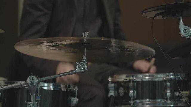 Batteur qui frappe sur une cymbale, crash, ride, splash avec sa baguette. Gros plan cam&eacute;ra.
