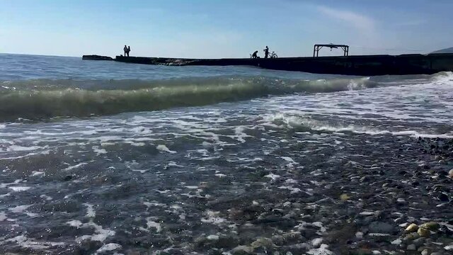 Sea coast with waves in sunny weather close-up. Waves on the Black Sea in Sochi. 4K video.