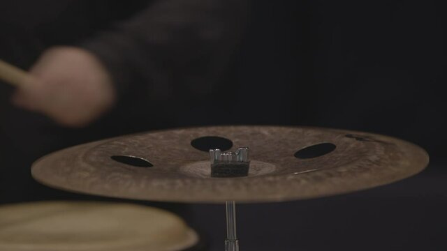 Batteur qui frappe sur une cymbale, crash, ride, splash avec sa baguette. Gros plan cam&eacute;ra.

