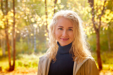 Portrait of a beautiful young woman in an autumn park on a yellow background with leaves