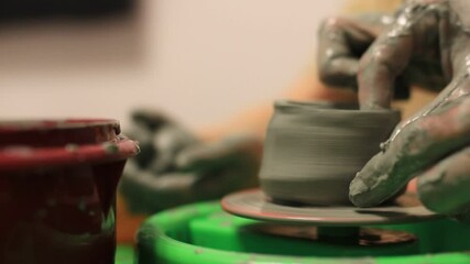 A close-up of a potter's hand creates a clay bowl on a potter's wheel. pottery training FullHD