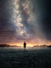 A man Exploring the night sky as the Milky Way galaxy fills the landscape from above. Photo...