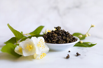 Chinese large leaf green tea with jasmine on white marble background, closeup