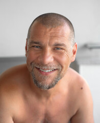 Portrait of a smiling mid-forties man with beard and short hair, without shirt