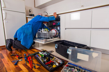 Handyman opening the dishwashers in white kitchen
