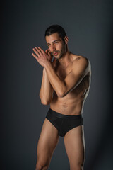 Fototapeta premium Fashion close-up portrait of a handsome male with bare torso posing in black underwear on isolated background