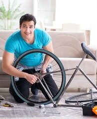 Obraz premium Young man repairing bicycle at home