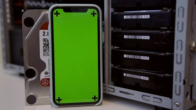 Mining bitcoins using cluster hard disk array on server or datacenter. Smartphone with green chroma key. New HDD