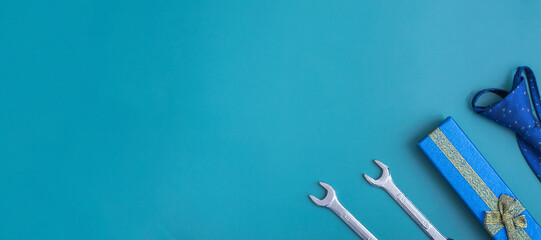 Father's day. Flat lay of gift box, tools and blue tie on blue background. Top view, copy space. Father's day concept. Banner