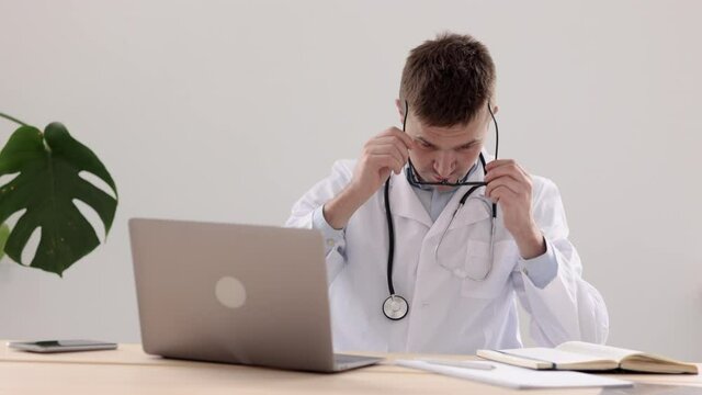 telemedicine, a European doctor in a white coat and glasses makes a note in a diary and a notebook entry, a Caucasian doctor in a hospital or clinic room makes a note in a notebook and prints on a