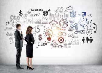 Businessman and businesswoman near business strategy sketch on grey wall