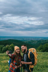 Couple of hikers taking selfie with a smartphone while walking in the nature