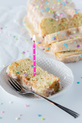 Slice of confetti loaf cake taken from above with a sliced loaf in behind.