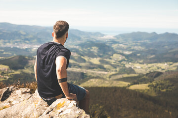Young caucasian man at the top of Oiz mountain with amazing views all over the green Basque country.