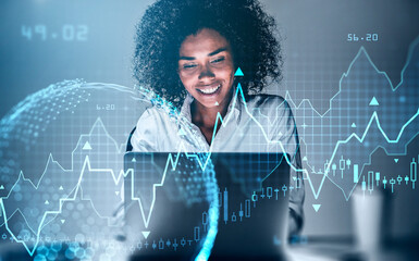 Smiling African-American businesswoman working on laptop researching financial news. Stock market changes candlesticks, data information icons. Globe projection. Concept of finance and technology