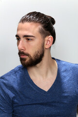 Fototapeta premium Attractive male model with long hair and beard posing in studio on isolated background. Style, trends, fashion concept.