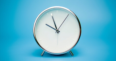Silver Alarm clock isolated on blue background, Showtime 09.57 am or pm..